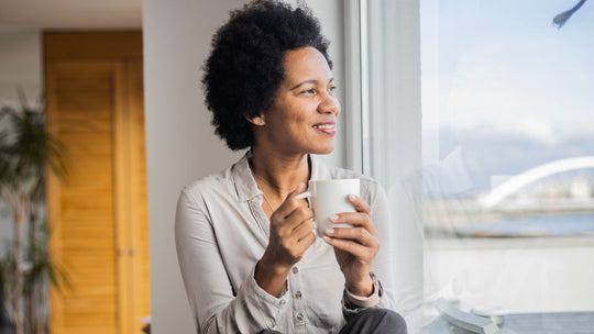black women looking out of window holding a cup of coffee