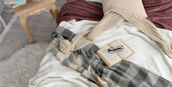 Book with reading glasses laid on an unmade bed