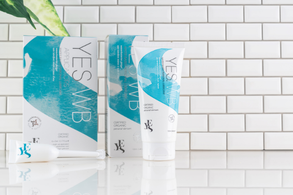 YES WB range on a white surface again a white tiled background. A tube of YES WB and an applicator as positioned at the front, with a plant in the background