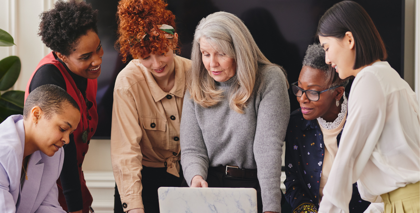 Group of women of different ages and ethnicities looking at a laptop