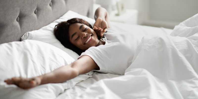 Smiling women laying in bed stretching 