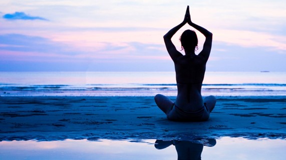Woman practicing yoga on a calm beach