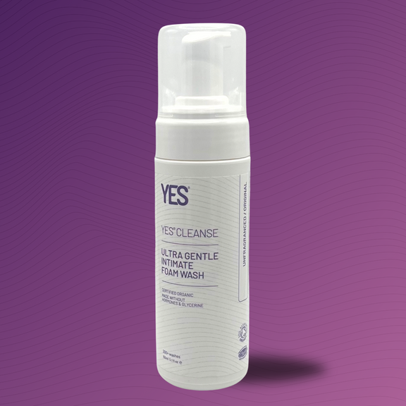 YES CLEANSE unfragranced intimate feminine wash on a purple gradient background with subtle contours.  Product is a 150ml  bottle with a pump dispensing top.  The product label is visible with the product name Ultra gentle intimate foam wash.  It is certified organic.  Made without hormones and glycerine