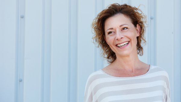 Testosterone replacement in menopause: Woman smiling on a white background 